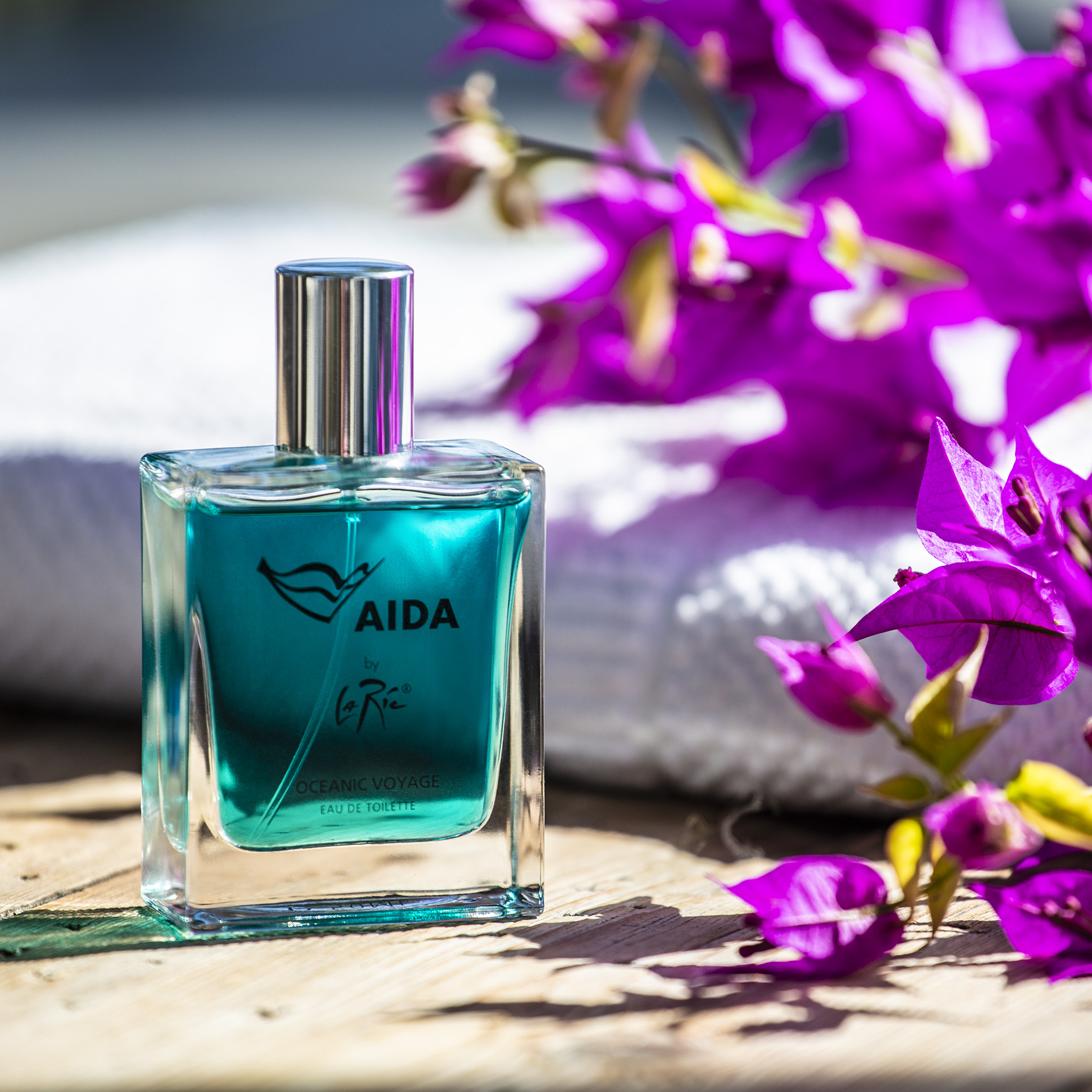 Transparenter, rechteckiger Glasflakon mit silbernem Zerstäuber und AIDA-Schifflogo in Rot auf der Vorderseite, daneben weiße Verpackung – Eau de Toilette ‚Oceanic Voyage‘ 50 ml